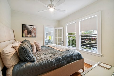A bedroom with a bed, pillows, a ceiling fan, and a window with blinds.
