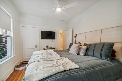 A bedroom with a bed, pillows, and a ceiling fan.