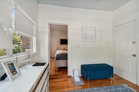 A bedroom with a bed, a bench, and a window.