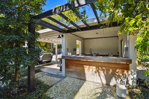 A modern house with a wooden pergola and a gravel garden.