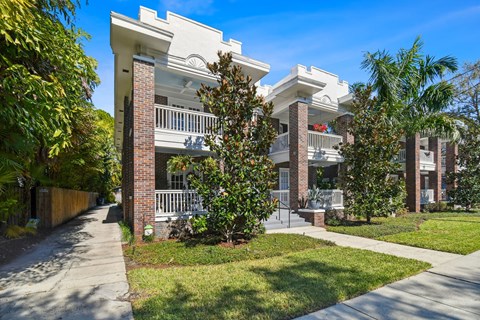 A white two-story house with a balcony and a small porch.