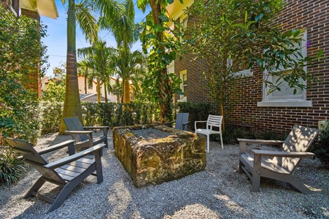 A patio with a bench, a table, and a tree.