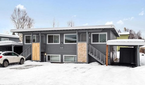 a home with a car garage in the snow