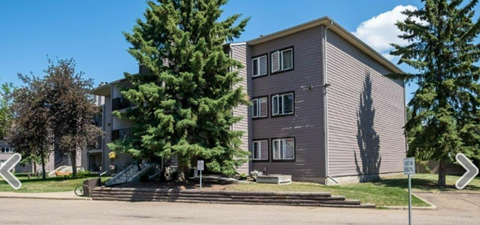 an apartment building on the corner of a street with trees