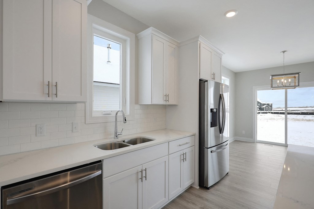 a kitchen with white cabinets and a stainless steel refrigerator