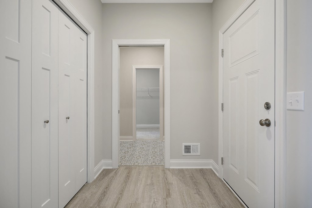 an empty hallway with white closets and wood floors