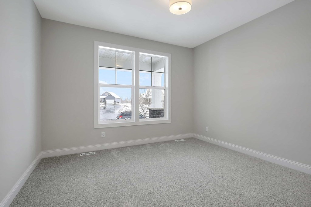 an empty room with a large window and carpet