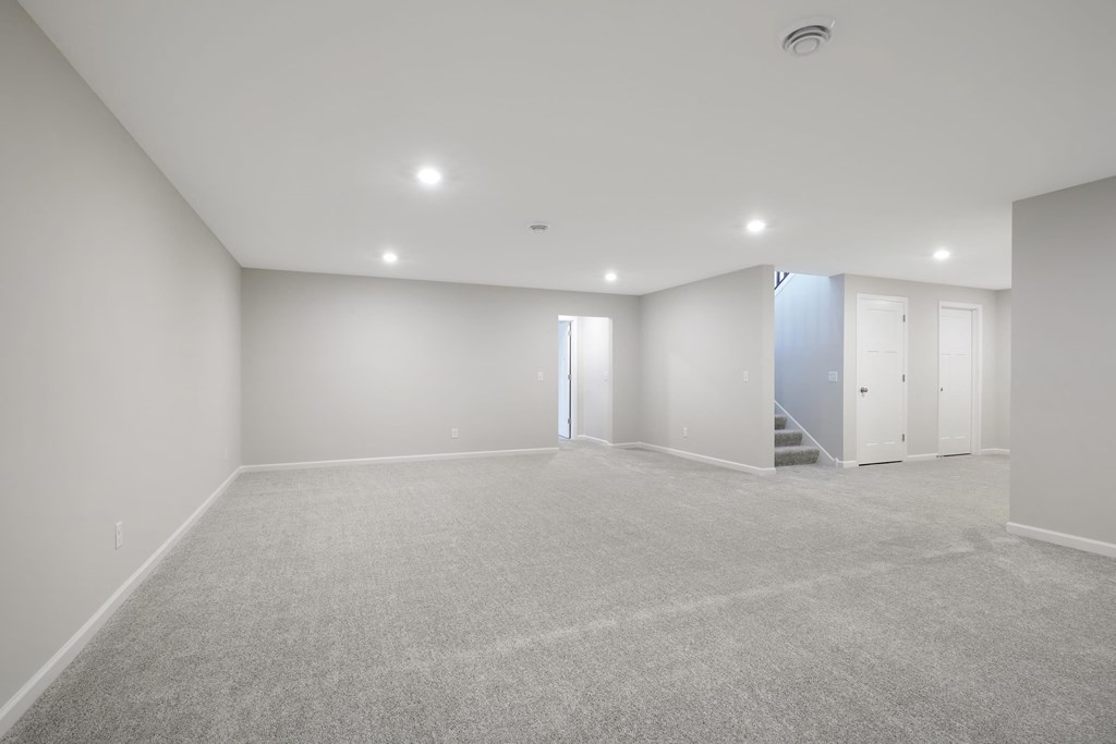 a room with carpet and white walls and a staircase