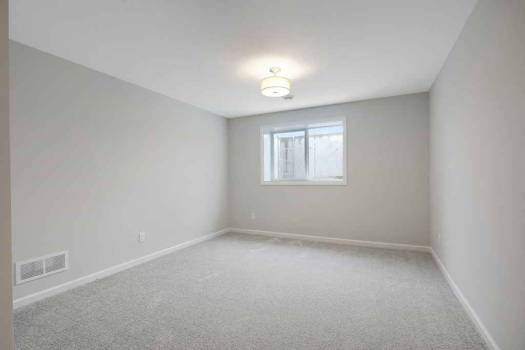 an empty room with a window and a ceiling lamp