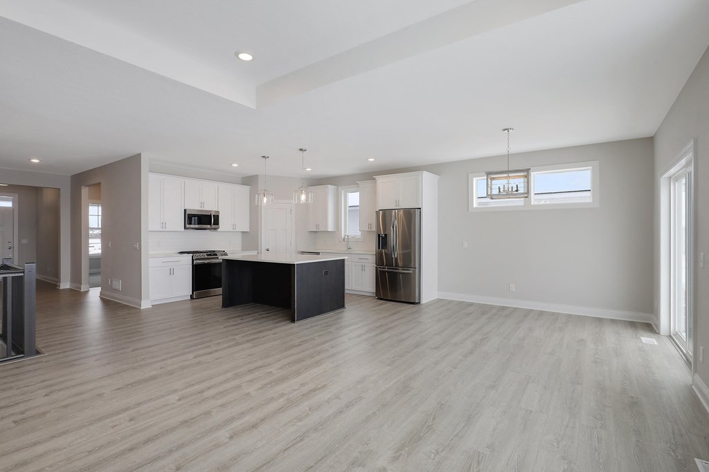 an open kitchen and living room with white cabinets and a black island