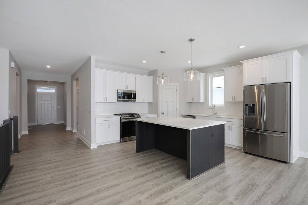 a kitchen with white cabinets and stainless steel appliances and a large island