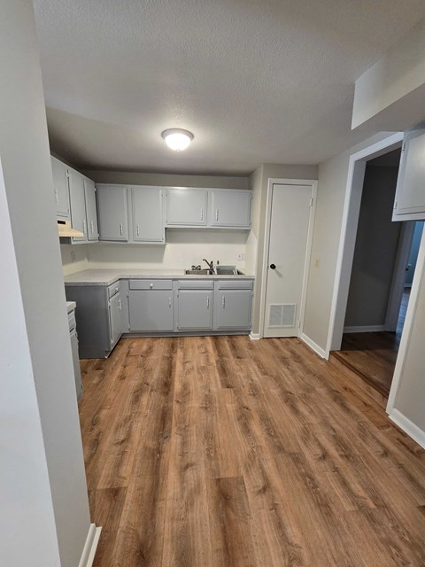 A kitchen with white cabinets and a wooden floor.