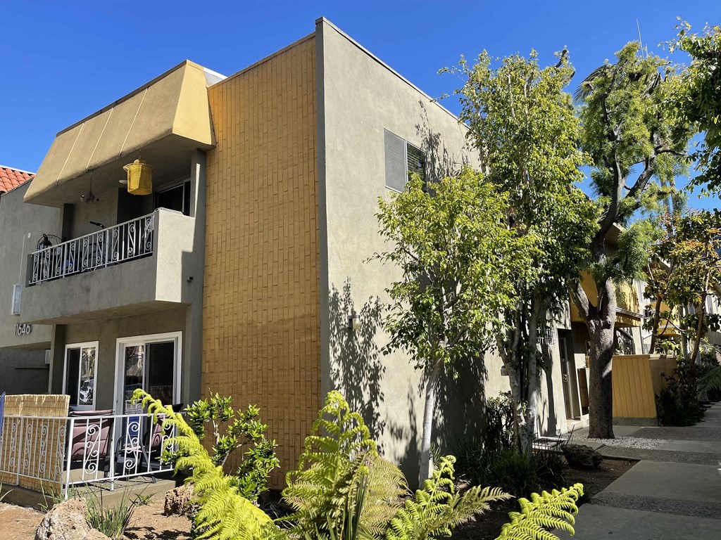 the front of a building with a balcony and trees