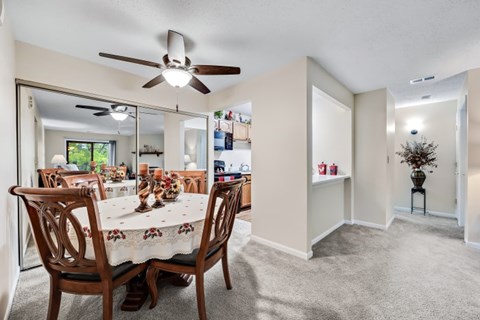 A dining room with a table set for six and a ceiling fan.
