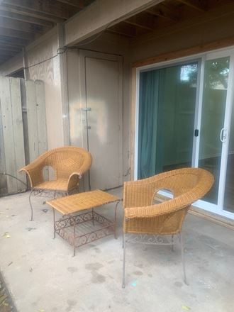 a pair of rattan chairs and a coffee table on a porch