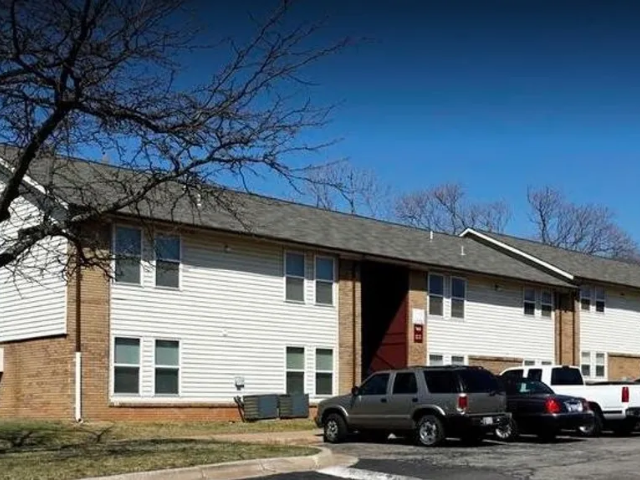 an apartment building with cars parked in a parking lot