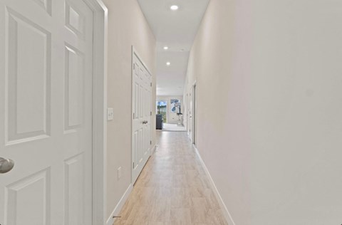 A long hallway with white walls and wood floors.