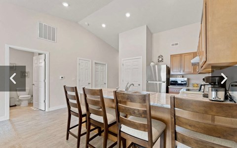 A kitchen with a table and chairs in the foreground.