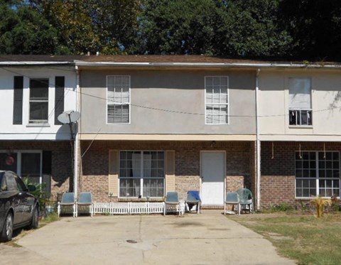 a white and brick building with chairs in front of it