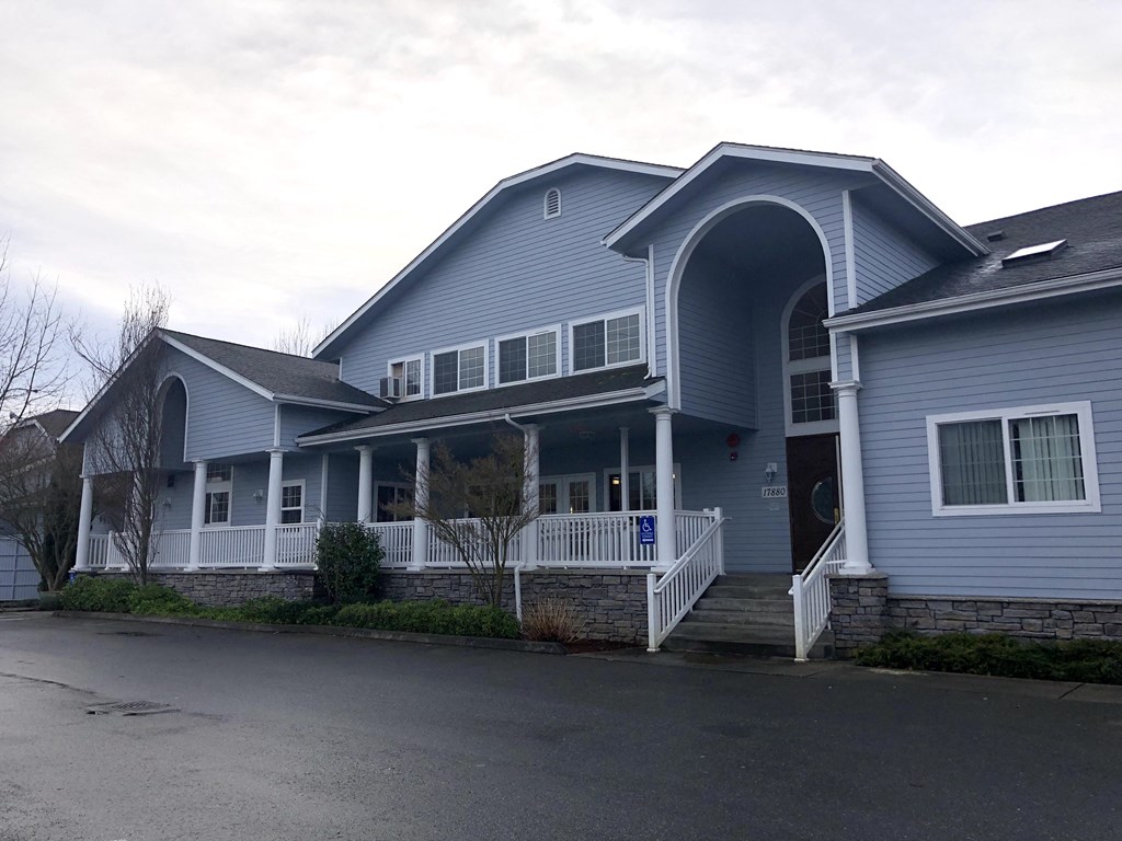 A blue house with a white porch and a black door.