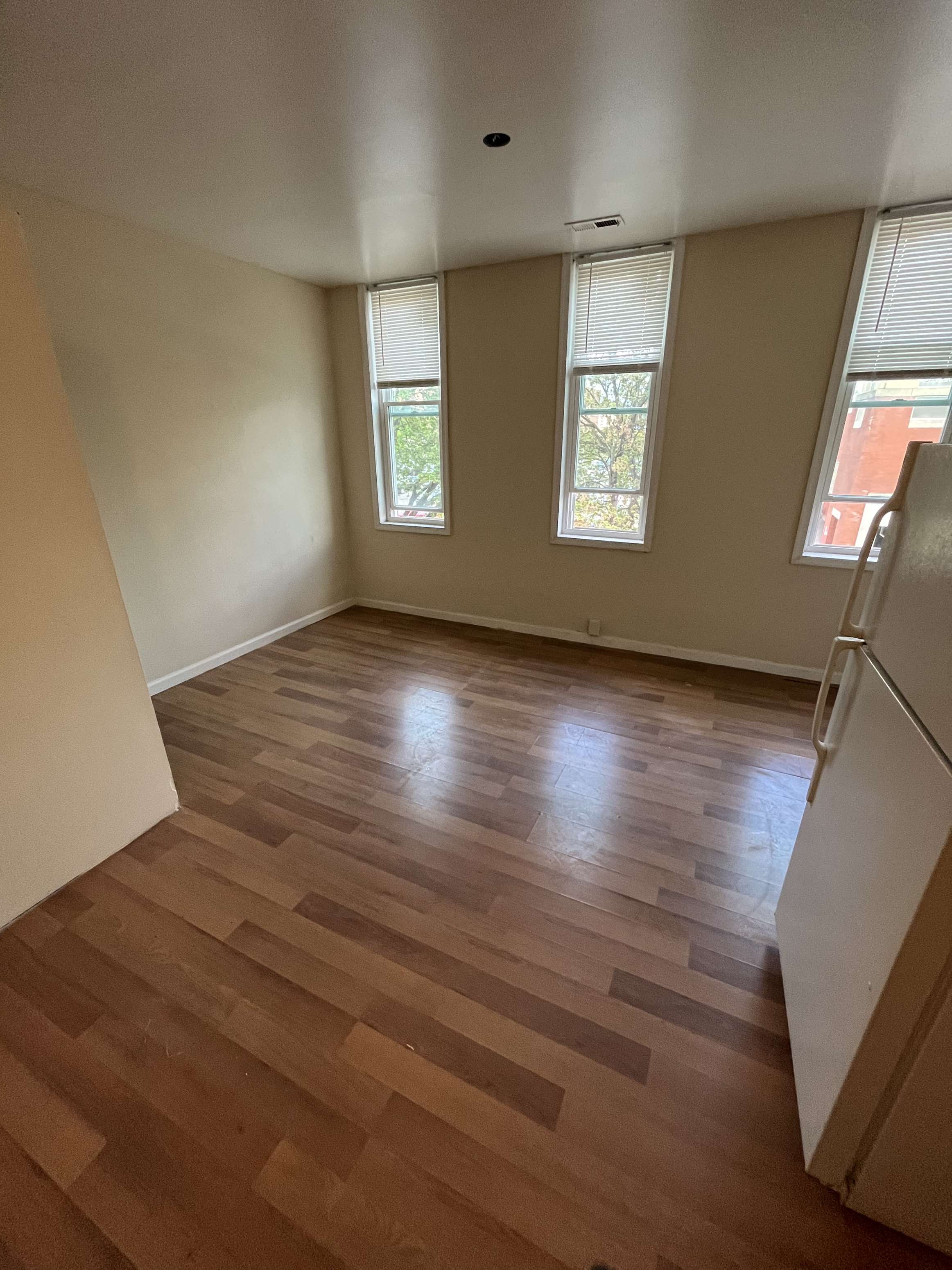 an empty living room with wooden floors and windows