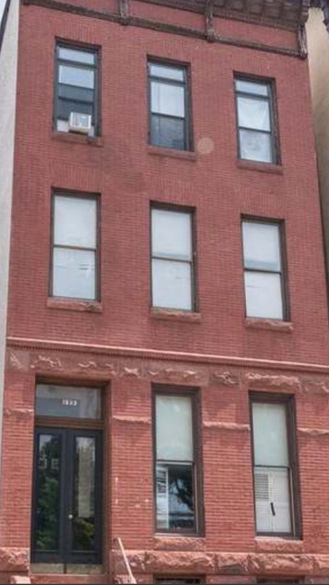 A red brick building with a black door and windows.