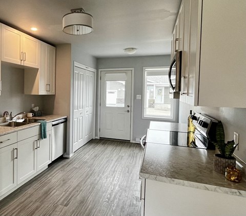 A kitchen with white cabinets and a grey floor.
