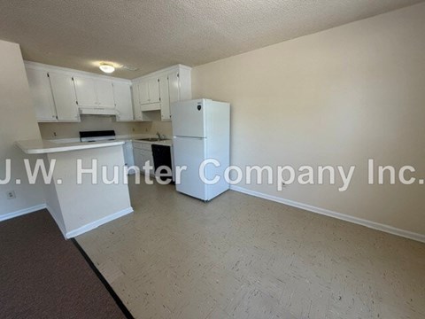 A kitchen with white cabinets and a white refrigerator.