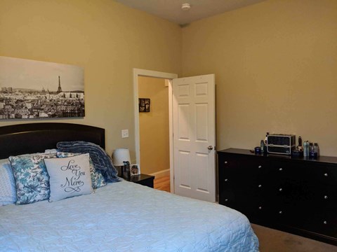 a bedroom with a bed and a dresser and a painting on the wall