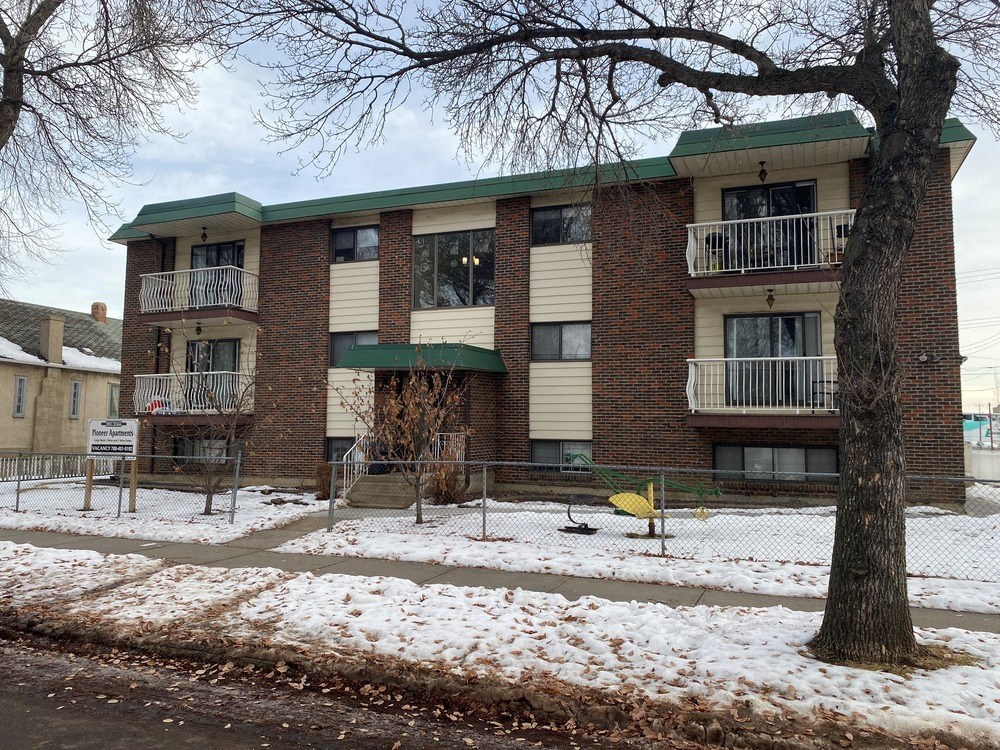 an apartment building with a yard and a tree in the snow