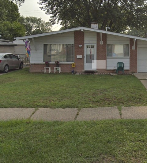 A small house with a white door and a green chair in front of it.