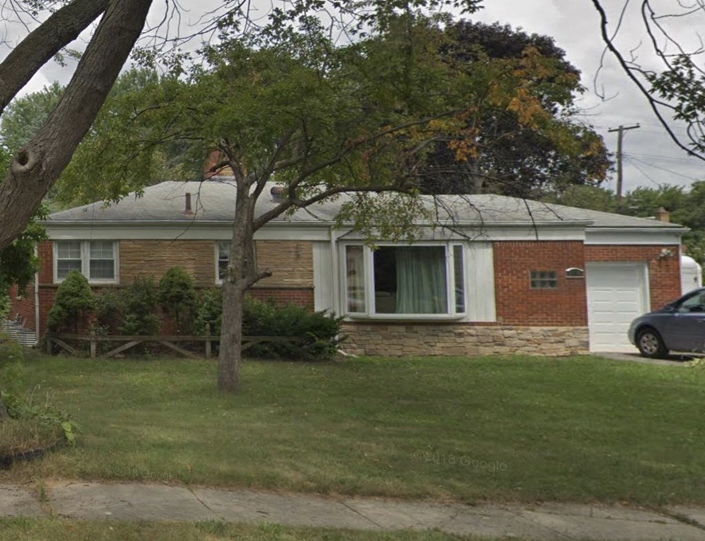 a small brick house with a tree in front of it