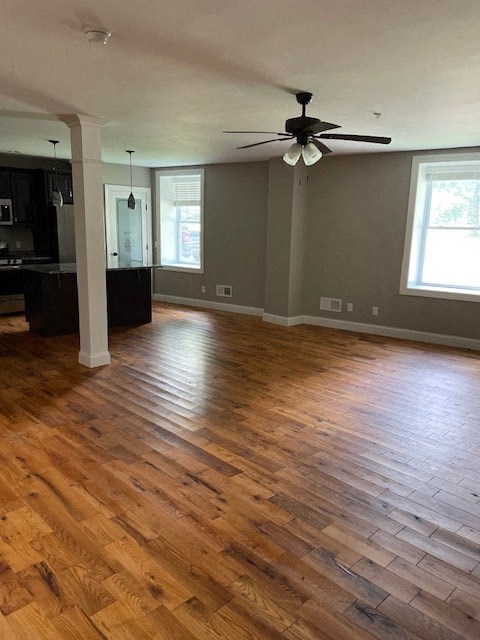 an empty living room with wood floors and a ceiling fan