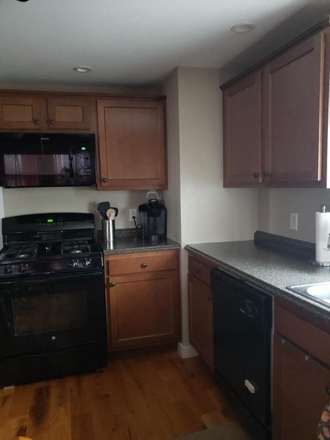 A kitchen with wooden cabinets and black appliances.