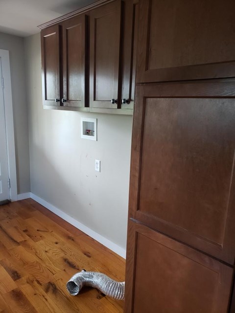 A room with wooden floors and a white wall with a switch.