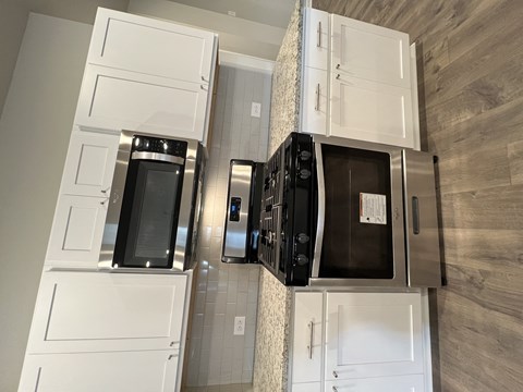 a kitchen with white cabinets and a counter top with microwave and ovens