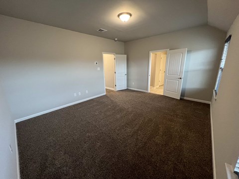 a living room with carpet and a door into a bedroom