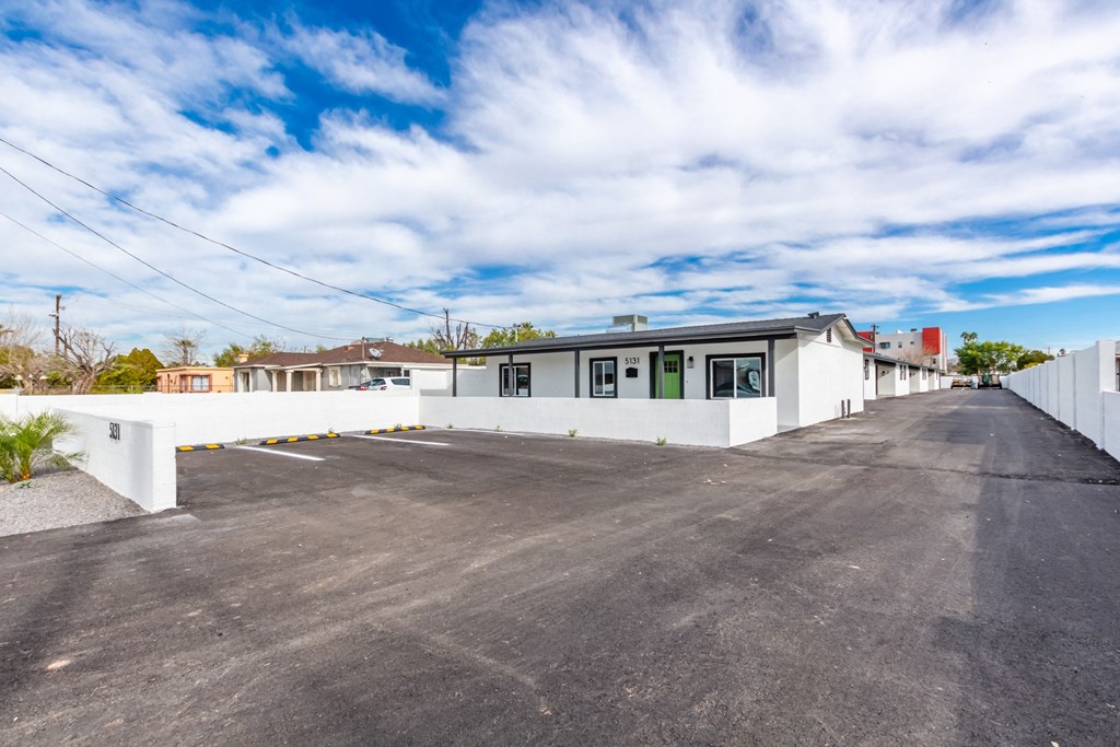 the exterior of a white house with a large parking lot