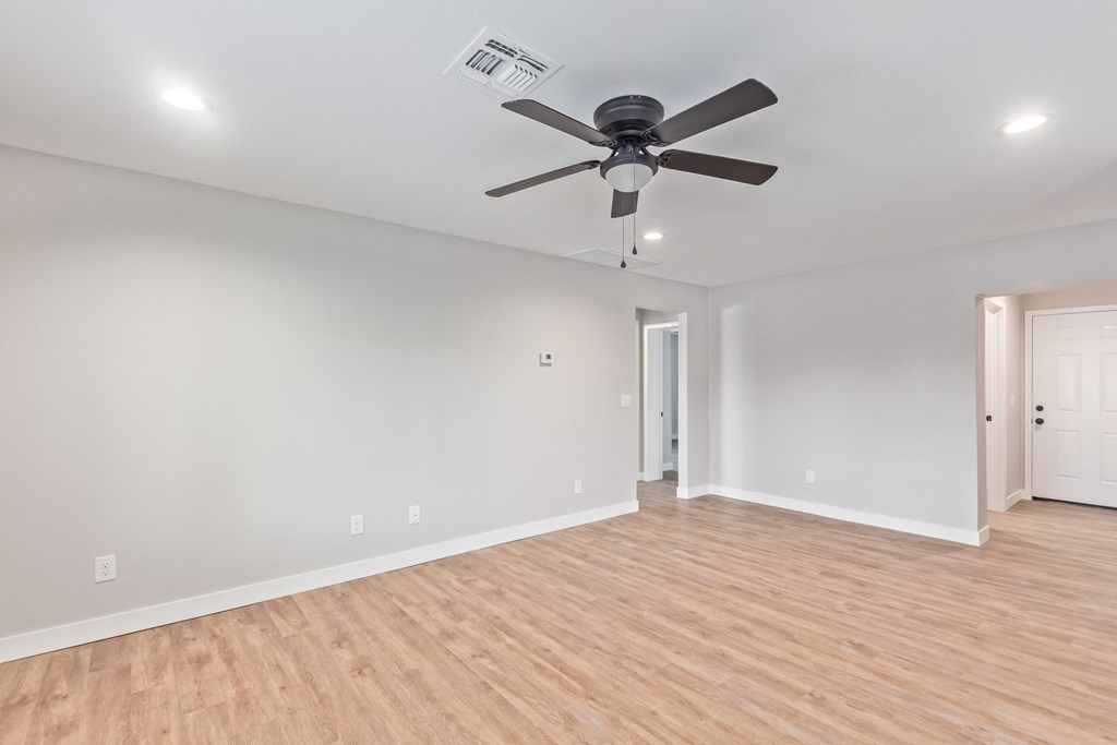 a living room with white walls and a ceiling fan