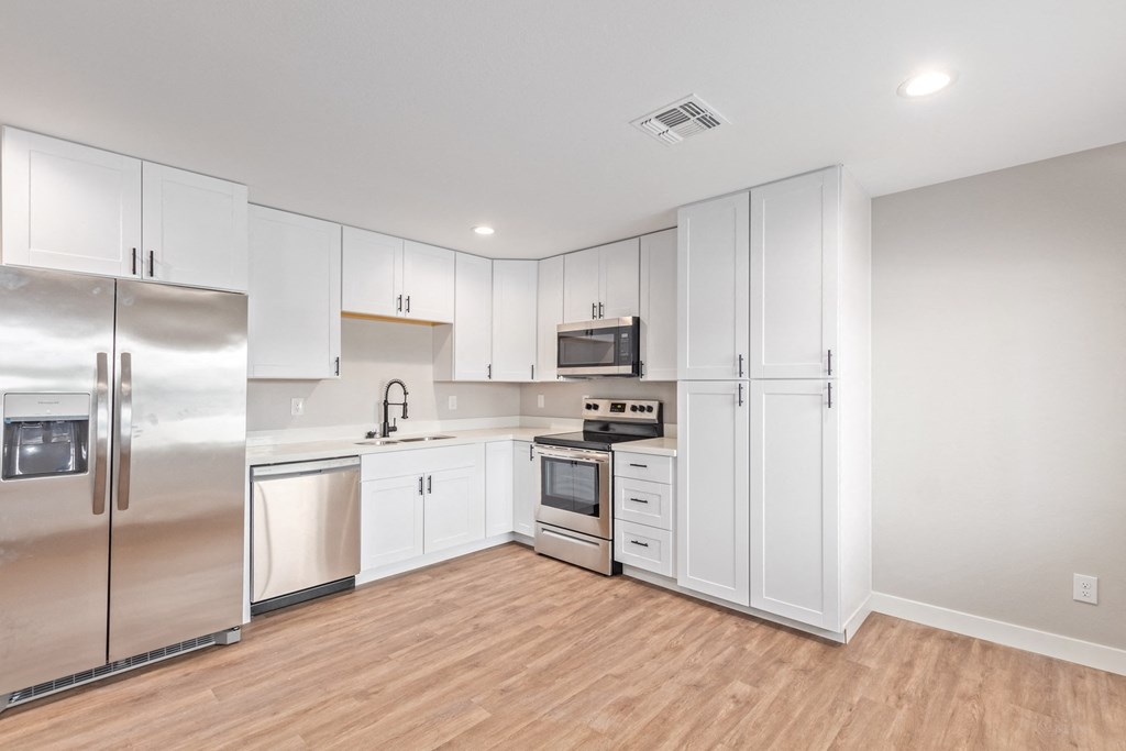 an empty kitchen with white cabinets and stainless steel appliances