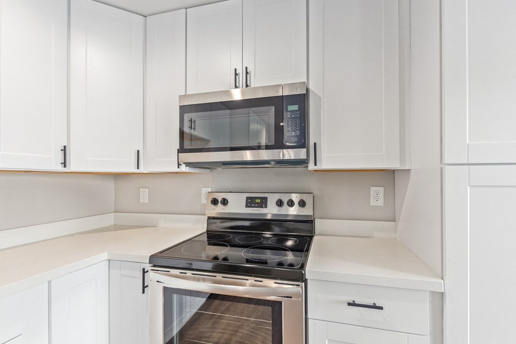 a kitchen with white cabinets and a stove and a microwave