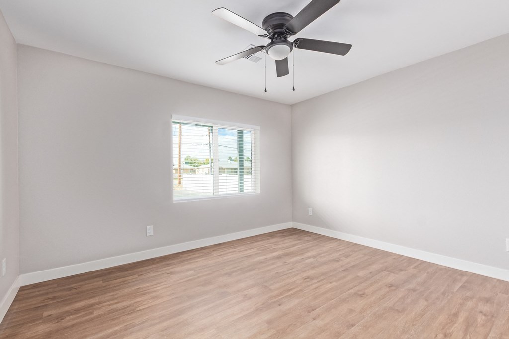 an empty room with a ceiling fan and a window