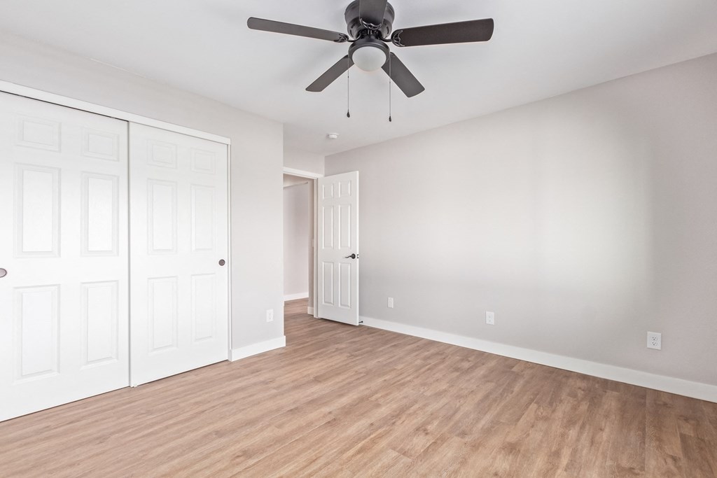 an empty living room with white walls and a ceiling fan