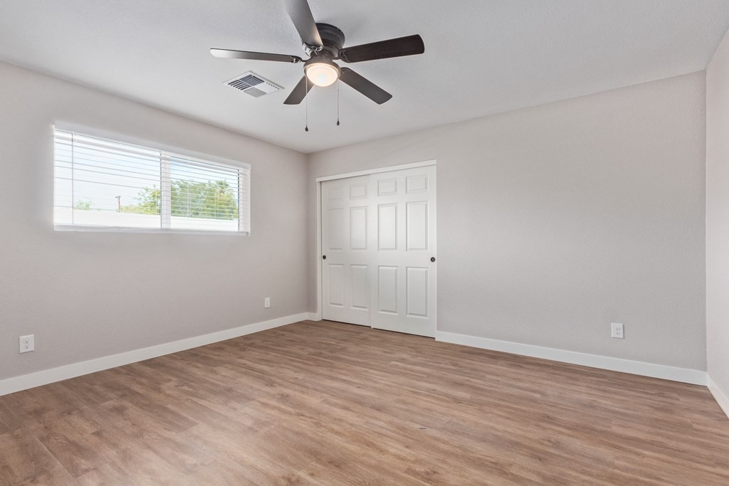 an empty living room with a ceiling fan and a window