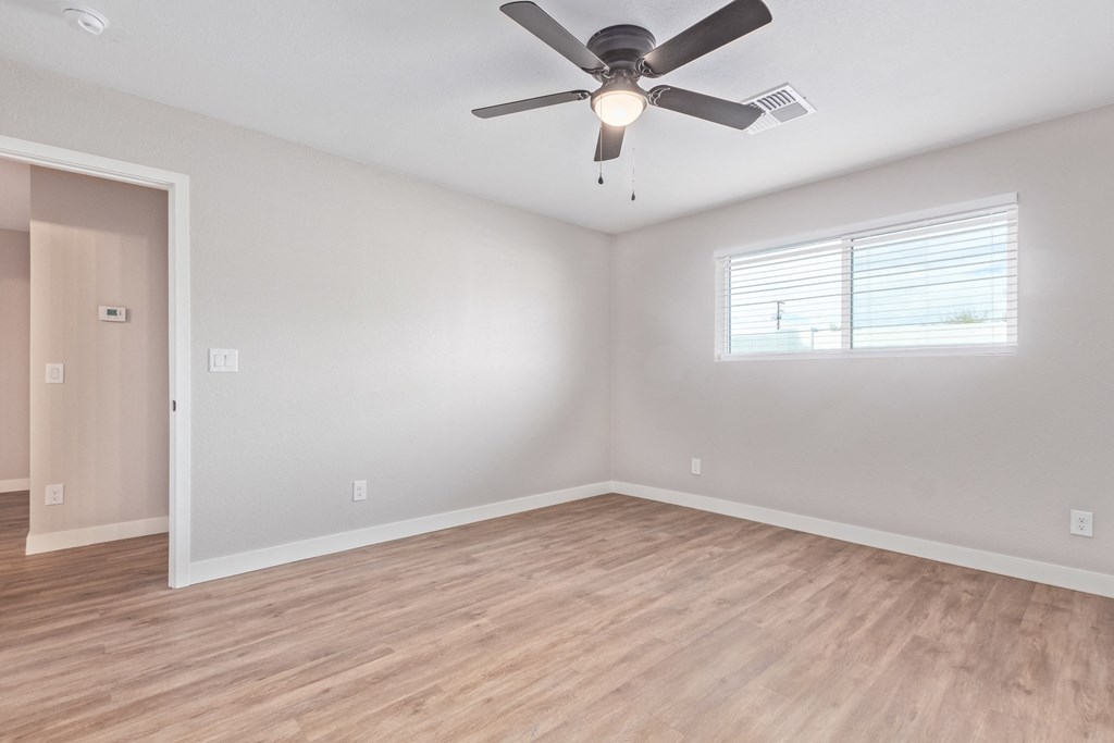 an empty room with a ceiling fan and a window