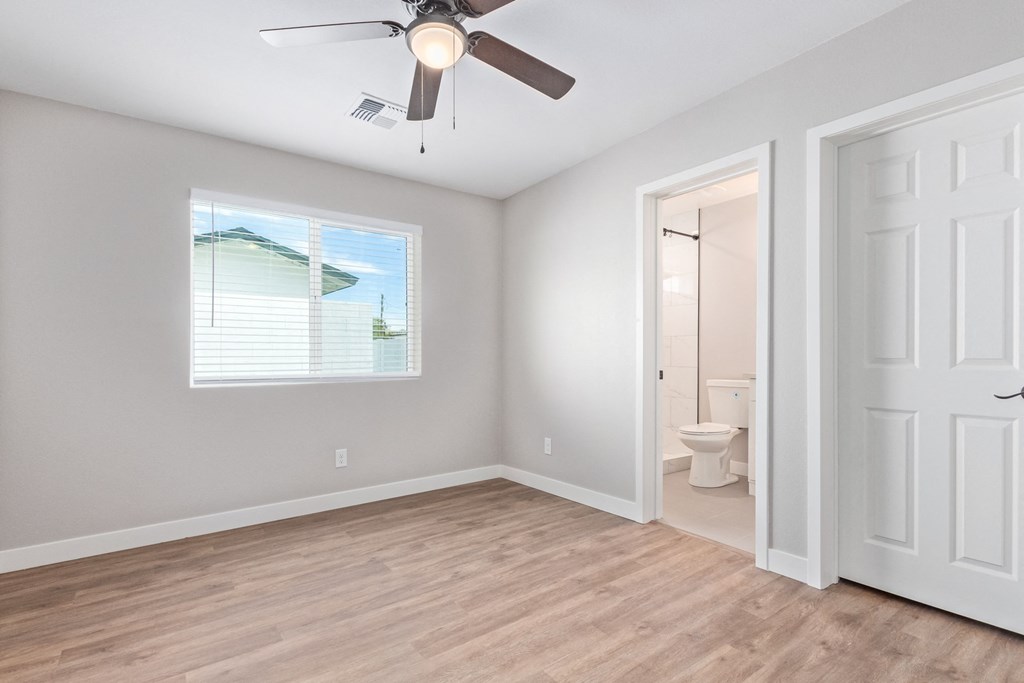 an empty bedroom with a ceiling fan and a bathroom