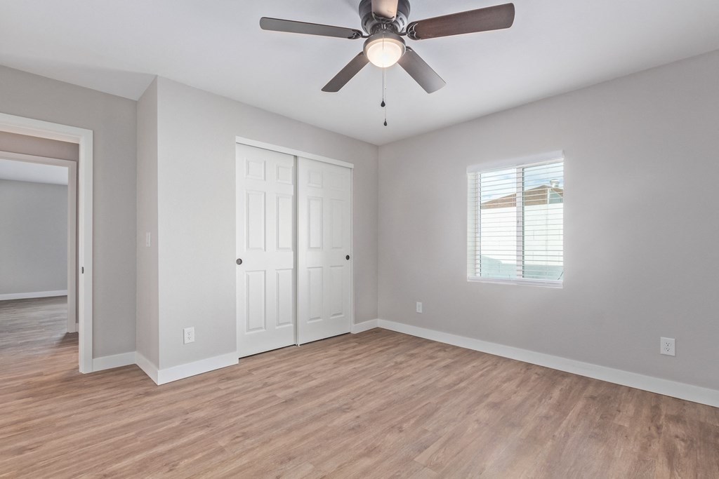 an empty living room with a ceiling fan and a door