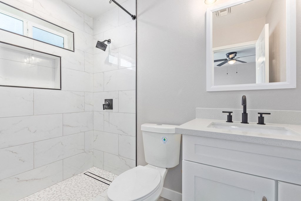 a white bathroom with a shower and a sink and a toilet