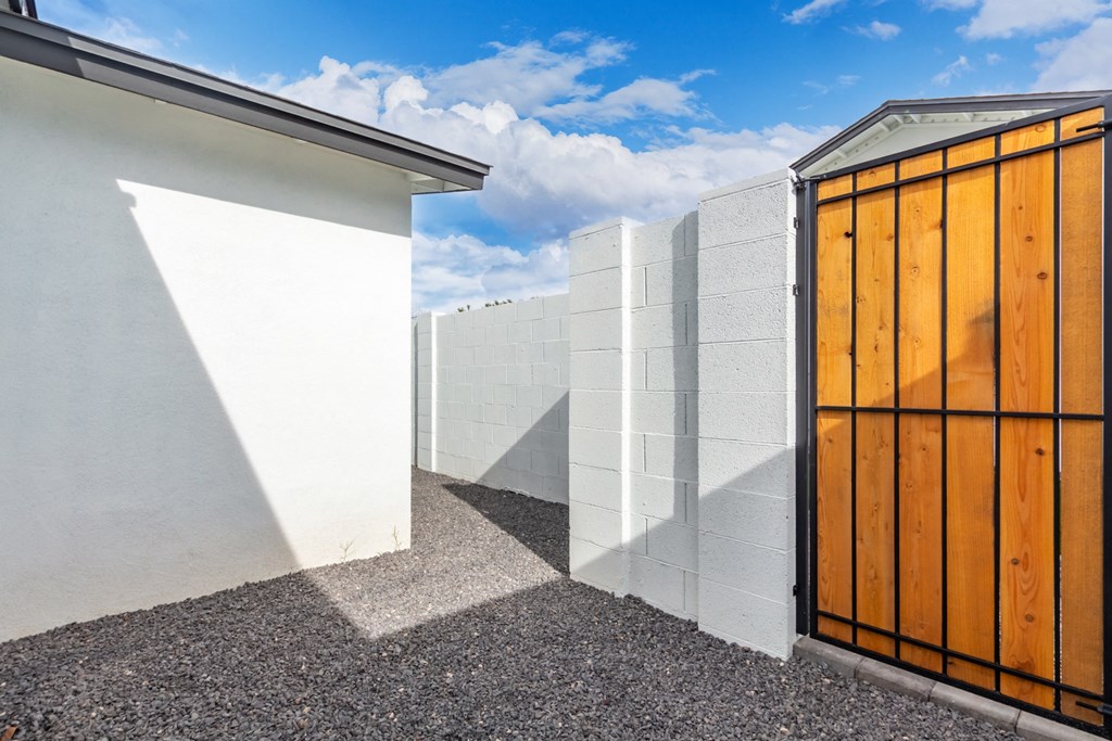 a white wall with a wooden door next to a white fence