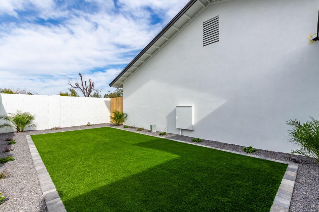 a backyard with a lawn and a white house